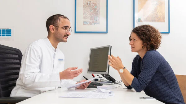 Patientin spricht mit Arzt, © Krebsinformationsdienst, DKFZ; Foto: Tobias Schwerdt Eine junge Frau sitzt einem Arzt am Schreibtisch gegenüber.