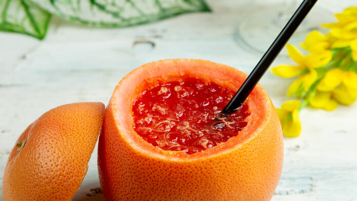 Ausgehöhlte Grapefruit mit Cocktail und Strohhalm
