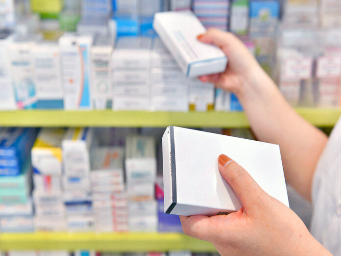 Apothekerin räumt Arzneimittel in das Apothekenregal ein.