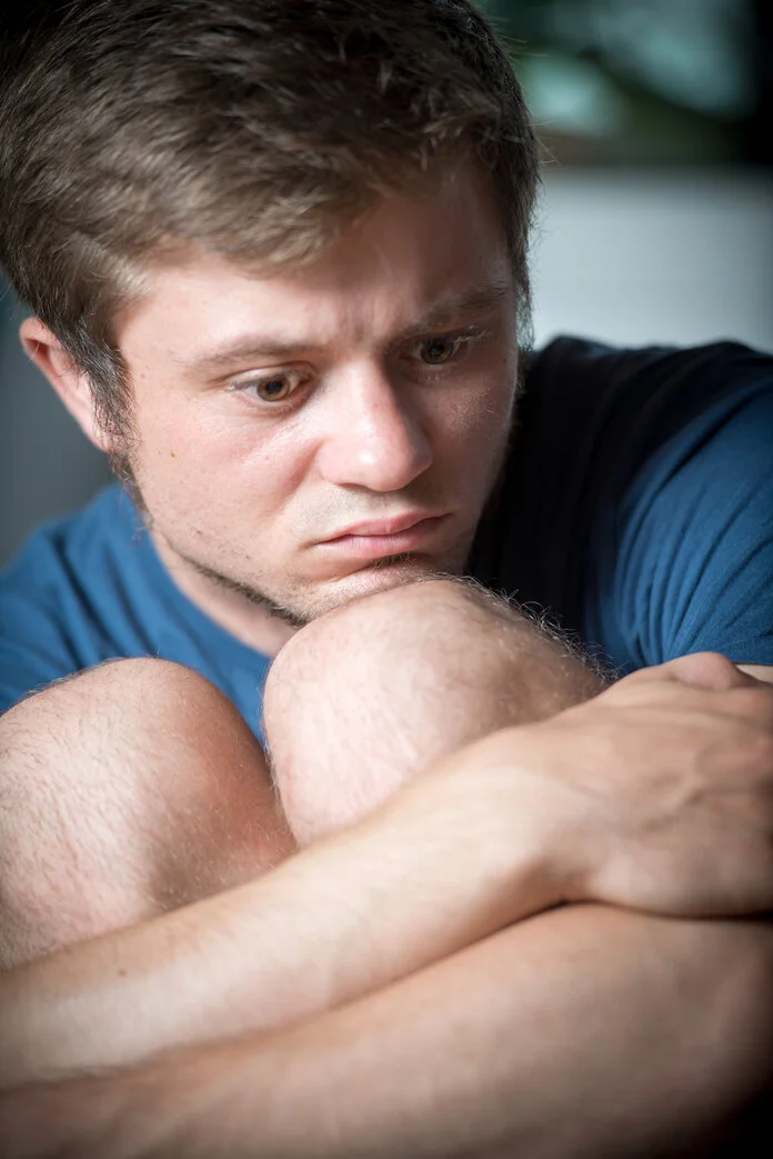 Trauriger junger Mann, © Krebsinformationsdienst, DKFZ; Foto: Tobias Schwerdt Junger Mann sitzt traurig schauend auf dem Sofa.