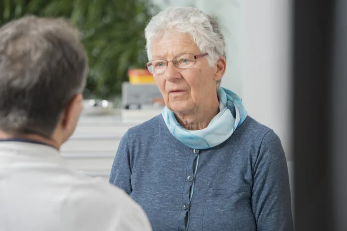 Beratungsgespräch in der Arztpraxis, © Krebsinformationsdienst, DKFZ; Foto: Tobias Schwerdt Eine ältere Patientin mit nachdenklichem Blick ist im Beratungsgespräch mit einem Mediziner in der Arztpraxis.