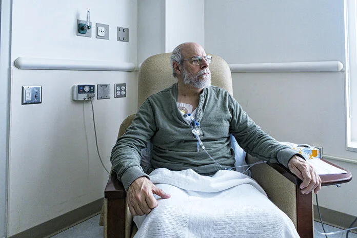 Patient, © Willowpix, iStock Mann sitzt in einem Krankenhausstuhl
