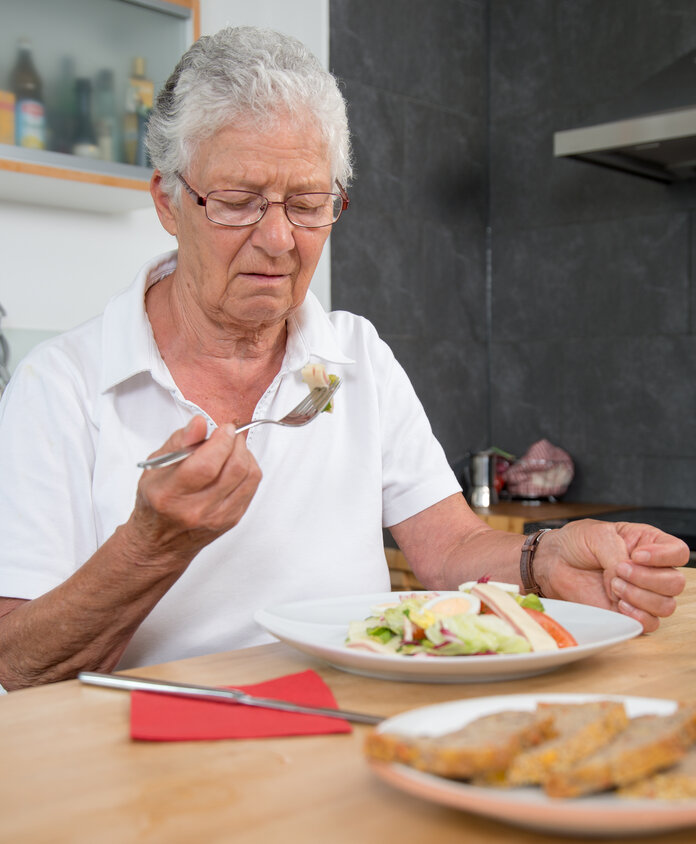 Appetitlosigkeit, © Krebsinformationsdienst, DKFZ; Foto: Tobias Schwerdt Ältere Frau sitzt am Esstisch und hat keinen Apetit beim Essen.