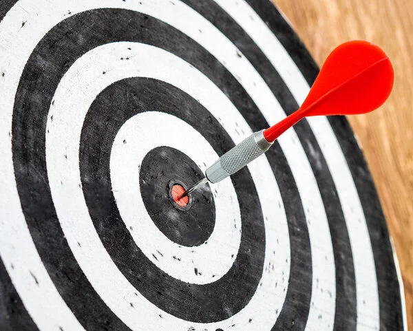 Zielscheibe, © TeroVesalainen, Pixabay (bearbeitet) Ein Dartpfeil steckt zielgenau im Bullseye einer Dartscheibe