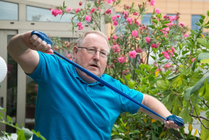 Ein älterer Mann macht Übungen mit einem Theraband.