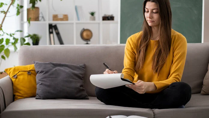 frau-jung-macht-notizen, @freepik Foto: Frau sitzt auf dem Sofa und macht sich Notizen