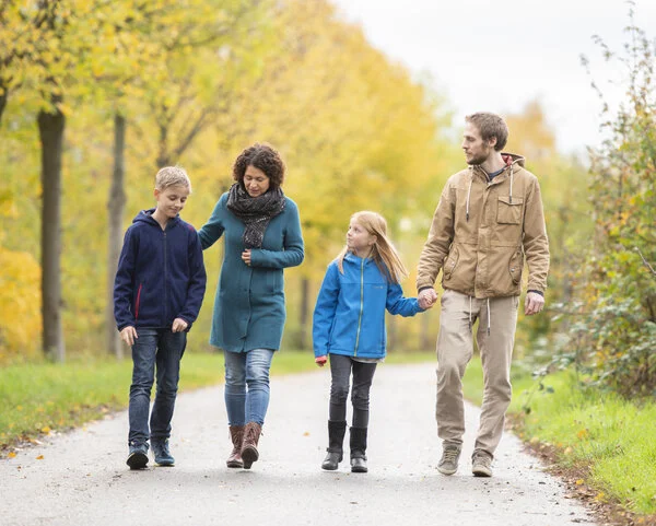 Familie geht spazieren, © Krebsinformationsdienst, DKFZ; Foto: Tobias Schwerdt Eine junge Frau und ein junger Mann gehen mit einem Mädchen und einem Jungen im Park spazieren unter unterhalten sich ernst.