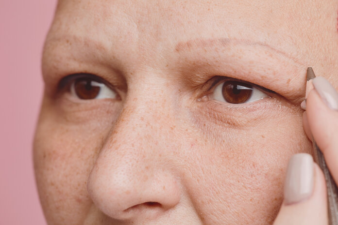 Schminken bei Krebs, © SeventyFour, Shutterstock.com Eine Krebspatientin zeichnet sich Augenbrauen nach. Zu sehen ist ein Ausschnitt ihres Gesichts.