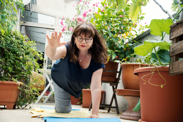 Frau macht Yogaübungen auf einem Balkon