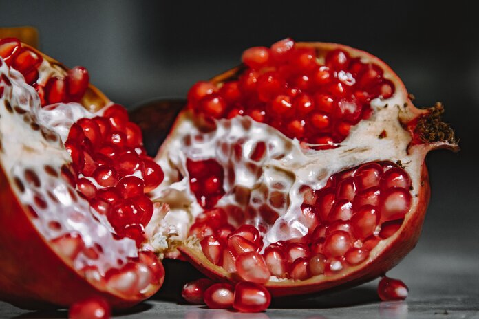 Granatapfel, in der Mitte aufgeschnitten, mit saftig-roten Kernen.