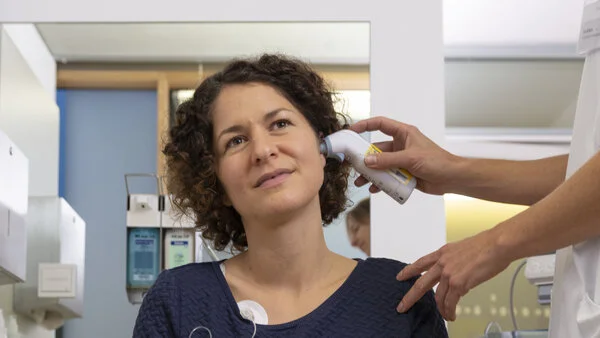 Fieber messen, © Krebsinformationsdienst, DKFZ; Foto: Tobias Schwerdt Patientin wird von einer Arzthelferin mit einem Infrarot-Thermometer Fieber gemessen.