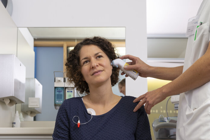 Fieber messen, © Krebsinformationsdienst, DKFZ; Foto: Tobias Schwerdt Patientin wird von einer Arzthelferin mit einem Infrarot-Thermometer Fieber gemessen.