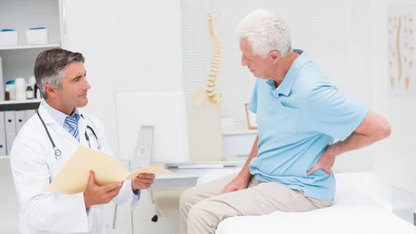 Arztgespräch Arzt spricht mit einem Patienten, der auf einer Liege sitzt