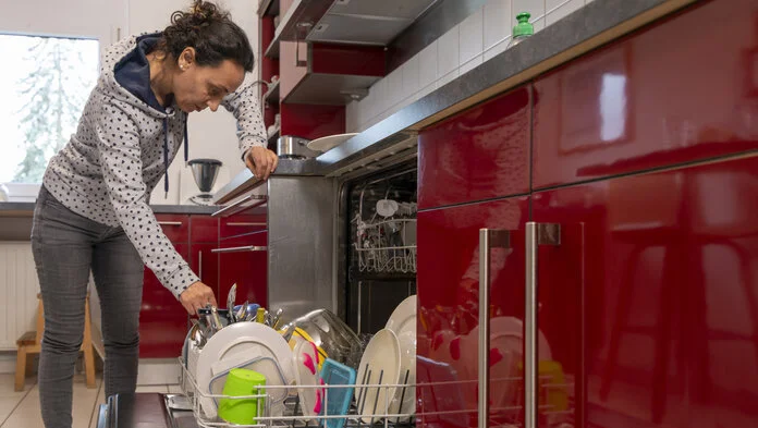 Hausarbeit, © Krebsinformationsdienst, DKFZ; Foto: Tobias Schwerdt Eine Frau mittleren Alters räumt die Spülmaschine aus und stützt sich dabei auf der Arbeitsplatte ab.