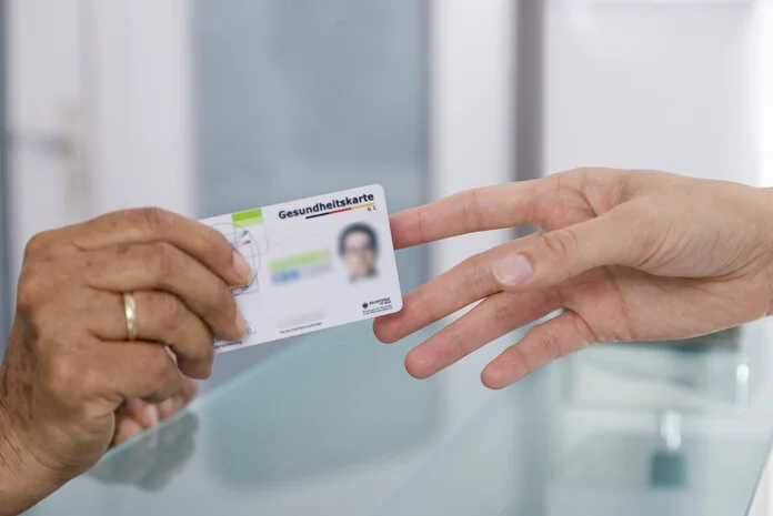 Versichertenkarte, © Krebsinformationsdienst, DKFZ; Foto: Tobias Schwerdt Eine Hand reicht einer anderen eine Versichertenkarte (Gesundheitskarte).