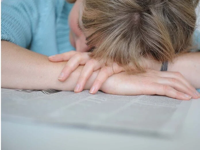 Frau liegt erschöpft auf einer Zeitung. Bild: Tobias Schwerdt © Krebsinformationsdienst, DKFZ
