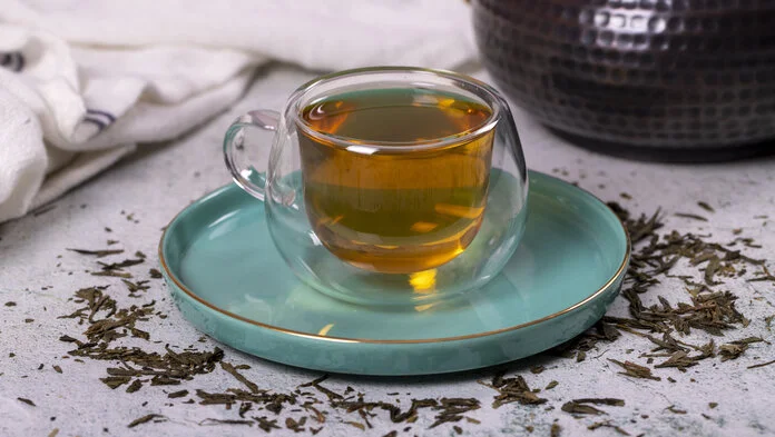Grüner Tee, © enezselvi, freepik Eine Tasse mit grünem Tee. Darum liegen Teeblätter.