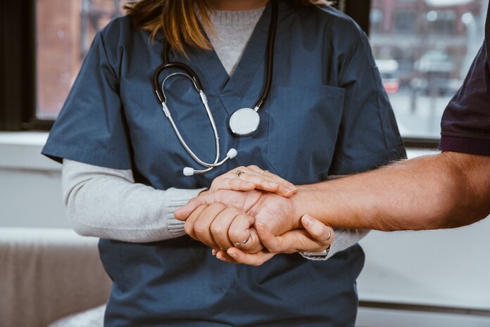 Unterstützung, © Nicole De Khors, Burst Pflegerin hält die Hand eines Patienten.