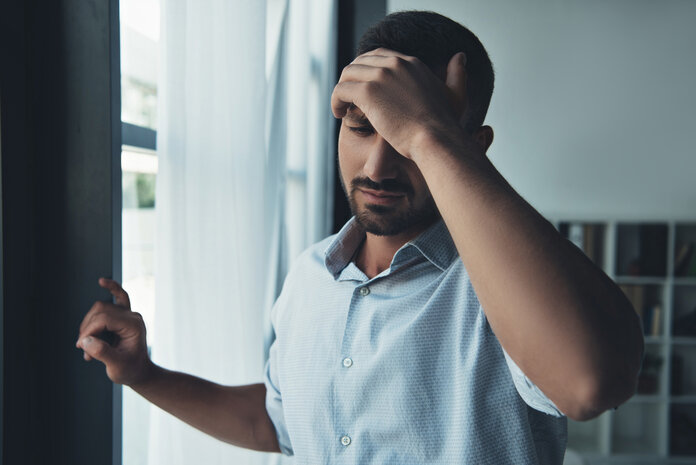 Sorgen und Kopfschmerzen, © LightFieldStudios, Thinkstock Junger Mann stützt sich an einer Wand und hält die linke Hand an die Stirn.