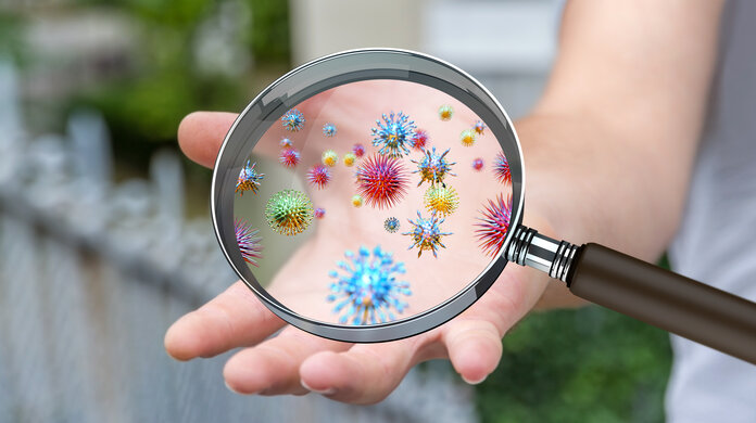 Keime, © sdecoret, Shutterstock Unter eine Lupe über einer Hand sind verschiedene Keime gezeigt.