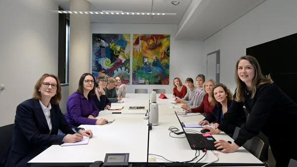 Mitarbeiterinnen des Krebsinformationsdienstes bei einer Präsentation, © Krebsinformationsdienst, DKFZ; Foto: Klaus Landry Mitarbeiterinnen des Krebsinformationsdienstes sitzen an einem Besprechungstisch und hören bei einer Präsentation einer Kollegin zu.