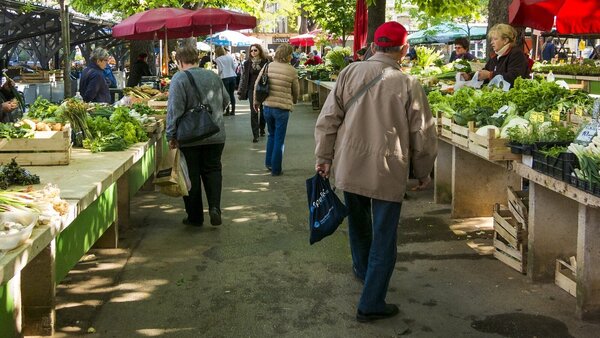 Menschen schlendern zwischen den Ständen eines Wochenmarktes.