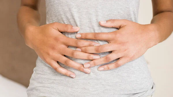 Person hält sich mit beiden Händen den Bauch