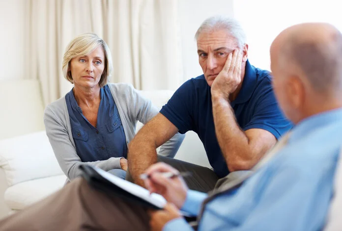 Beratungsgespräch, © Squaredpixels, Getty Images Älteres Ehepaar sitzt auf einer Couch und spricht mit einem Psychologen.