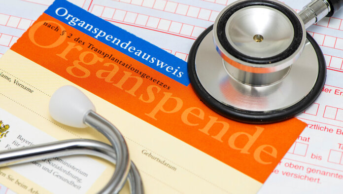 Ein Organspendeausweis und ein Stethoskop liegen auf einem Tisch.
