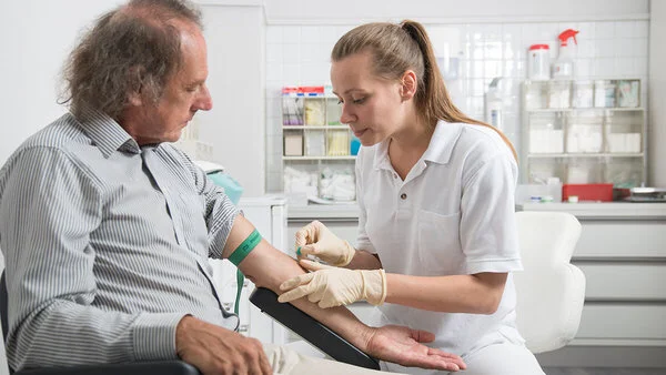 Blutentnahme. Foto: Tobias Schwerdt Arzthelfein nimmt bei einem Mann Blut ab.