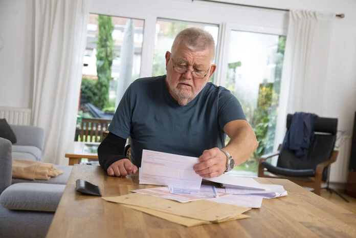 Medizinische Dokumente, © Krebsinformationsdienst, DKFZ; Foto: Tobias Schwerdt Ein älterer Mann sitzt am Wohnzimmertisch und sortiert medizinische Dokumente.