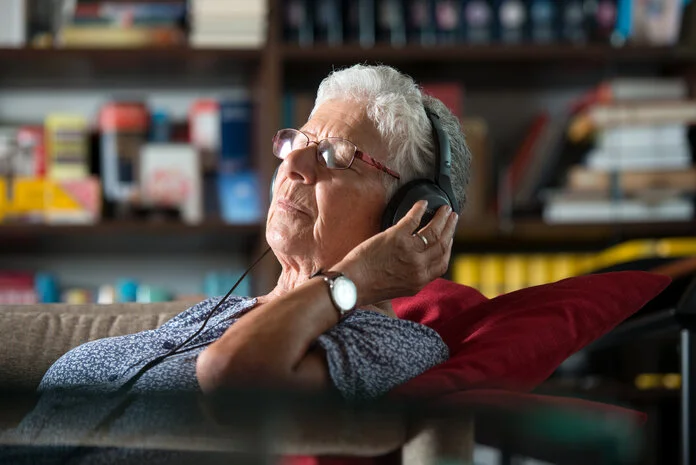 Musik hören, © Krebsinformationsdienst, DKFZ; Foto: Tobias Schwerdt Ältere Frau beim Musikhören mit Kopfhörer auf einem Sofa.