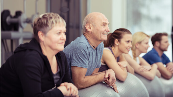 Menschen machen Sportübungen mit Gymnastikbällen.