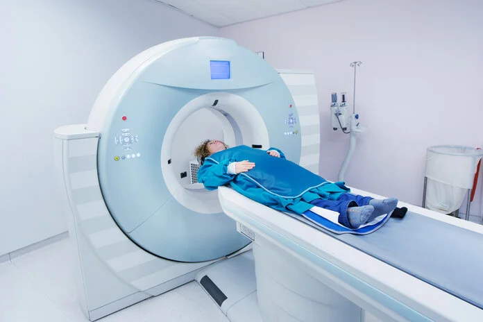 Schutzkleidung bei einer Computertomographie, © KaliAntye, Shutterstock Eine Frau trägt eine Bleiweste und liegt auf dem Untersuchungstisch eines Computertomographen.