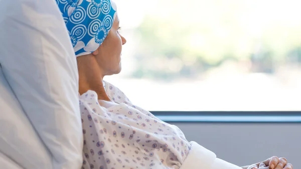Patientin mit Kopftuch, © Rido, Shutterstock Patientin mit Kopftuch liegt im Krankenbett und schaut aus dem Fenster.
