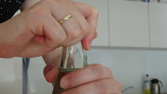 Wasserflasche öffnen, © Krebsinformationsdienst; DKFZ Hände öffnen den Drehverschluss einer Wasserflasche.