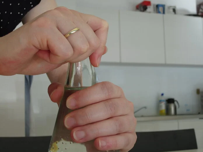 Wasserflasche öfnnen, © Krebsinformationsdienst; DKFZ Weibliche Hände öffnen den Drehverschluss eine Wasserflasche