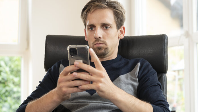 Ein Mann schaut auf den Bildschirm eines Smartphones.