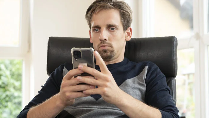 Ein Mann schaut auf den Bildschirm eines Smartphones.