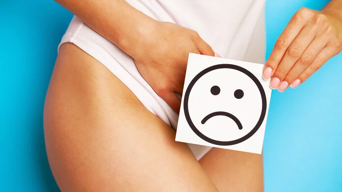 Vaginalprobleme, © maksymiv_yura, freepik Ausschnitt einer Frau in Unterwäsche, die ein Schild mit einem traurigen Smiley vor ihren Genitalbereich hält.