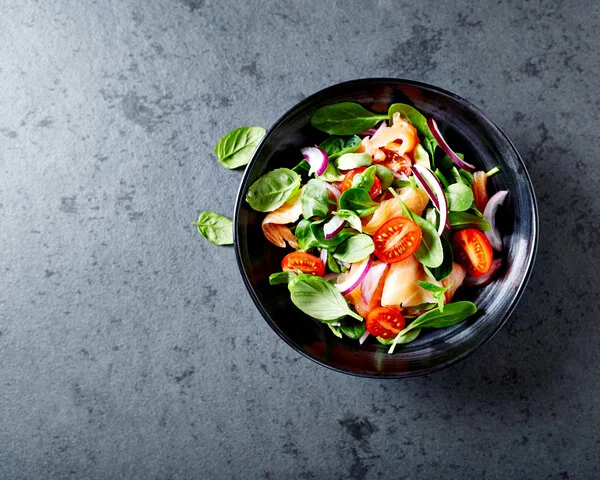 Salat, © Barbara Dudzinska, Shutterstock Salat mit Tomaten und Lachs auf grauem Tisch