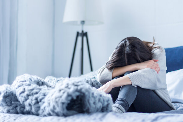 Traurige, depressive Frau sitzt auf dem Bett