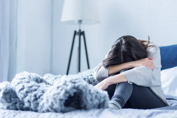 Traurige, depressive Frau sitzt auf dem Bett