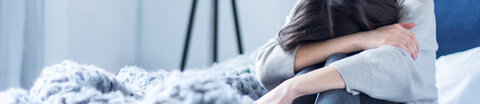 Traurige, depressive Frau sitzt auf dem Bett