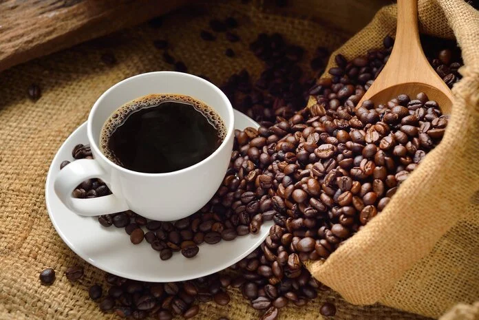 Kaffee , © Diego Leite, Pixabay Eine Tasse schwarzer Kaffee steht auf einem Tisch. Rechts daneben ist ein Jutebeutel mit Kaffeebohnen und einem Holzlöffel.