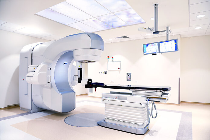 Untersuchungsraum mit elektrischer Untersuchungsliege und Linearbeschleuniger zur Strahlentherapie.