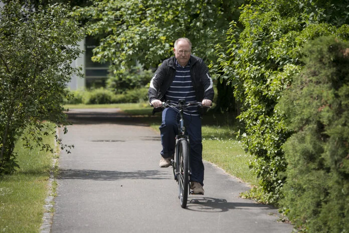 Älterer Mann fährt entspannt im Grünen Fahrrad., Krebsinformationsdienst, Deutsches Krebsforschungszentrum Älterer Mann fährt im Grünen Fahrrad.