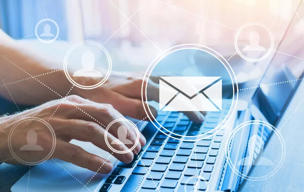 Vernetzt über das Internet © anyaberkut, iStock, © anyaberkut, iStock Hände tippen auf eine Laptop-Tastatur. Ausgegraute Briefumschlag. und Menschen-Icons über dem Bild deuten eine Vernetzung an
