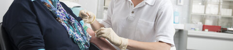 Eine Arzthelferin nimmt einer Patientin Blut ab.