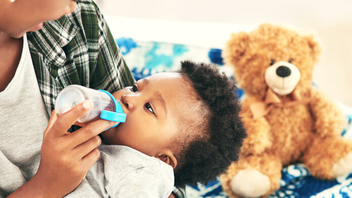 Frau füttert ein Baby mit einem Fläschchen Tee